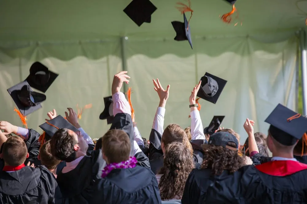 Estudiantes lanzando sus birretes al aire el día de su graduación